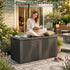 Black 260 gallon outdoor storage box with sculptural wave design in a landscaped patio seating area.