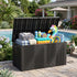 Open black 260 gallon deck box storing pool floats, towels and accessories beside an outdoor swimming pool.