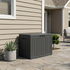 50 gallon black outdoor storage deck box placed against house wall for backyard organization