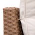 Beige outdoor sofa cushion with fabric attachment strap against woven wicker frame