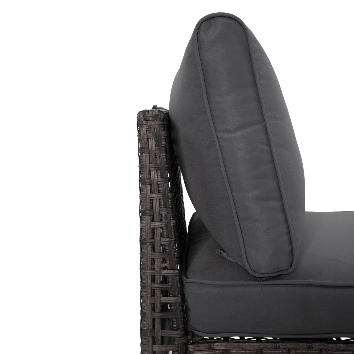 Thick grey patio sofa seat cushion above open-weave wicker base